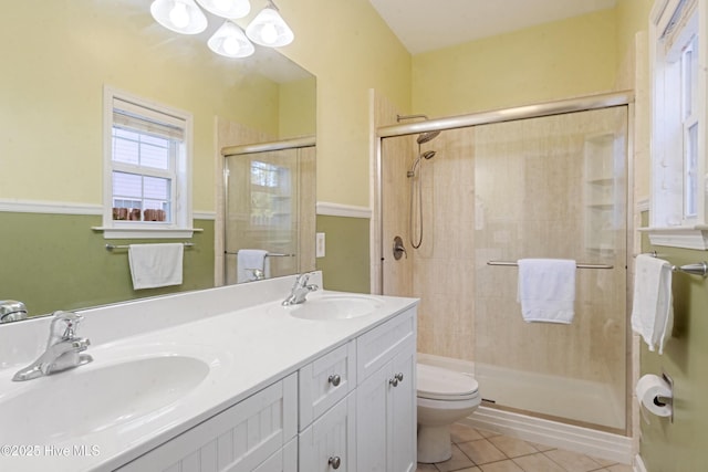 bathroom featuring tile patterned flooring, vanity, a shower with shower door, and toilet