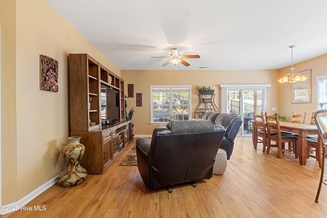 living room with ceiling fan with notable chandelier and light wood-type flooring