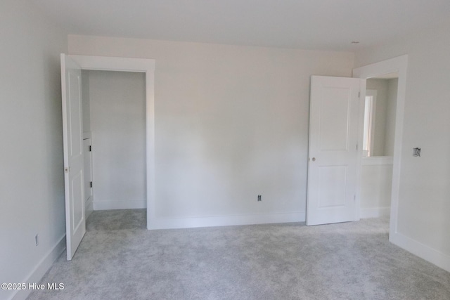 unfurnished room featuring light carpet and baseboards