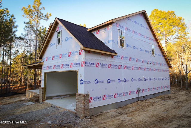 view of side of property featuring a garage and roof with shingles