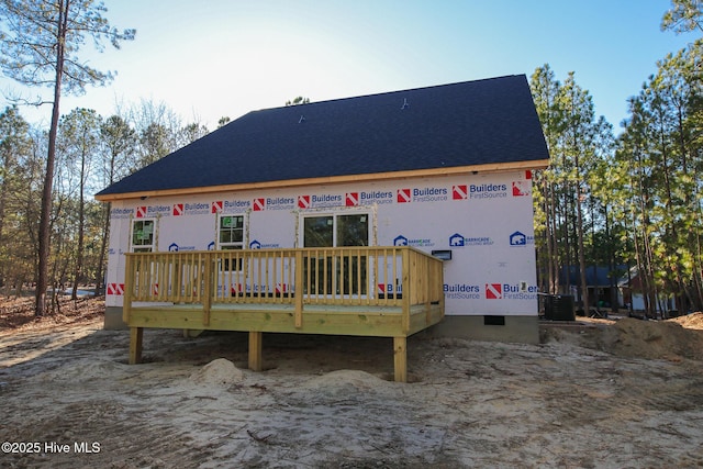 rear view of property with cooling unit and roof with shingles