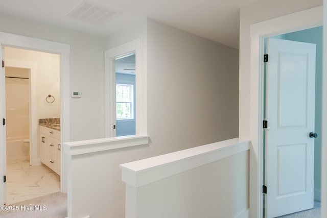 hall with marble finish floor, an upstairs landing, and visible vents
