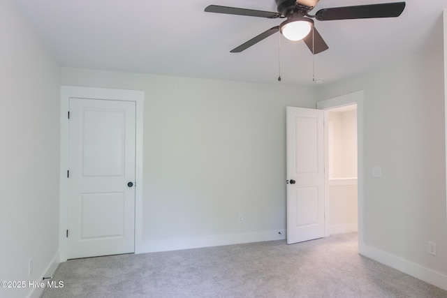 spare room featuring light carpet, a ceiling fan, and baseboards