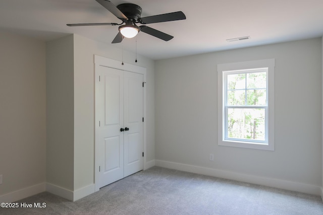 unfurnished bedroom with light carpet, visible vents, baseboards, a closet, and ceiling fan