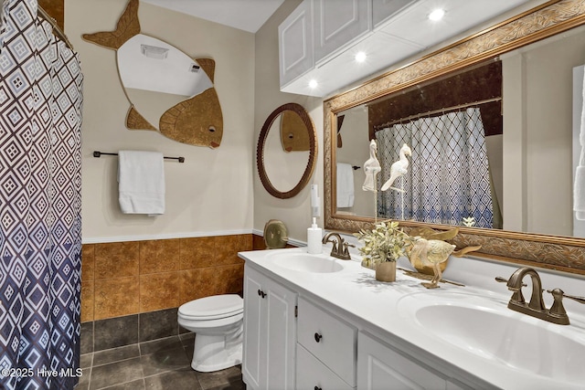 bathroom featuring tile patterned flooring, vanity, tile walls, and toilet