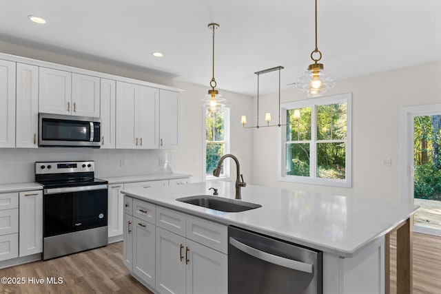 kitchen with sink, white cabinetry, a center island with sink, stainless steel appliances, and decorative backsplash