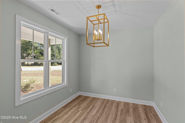 unfurnished dining area with a chandelier and hardwood / wood-style floors