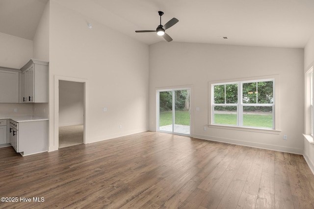 unfurnished living room with ceiling fan, dark hardwood / wood-style flooring, and high vaulted ceiling