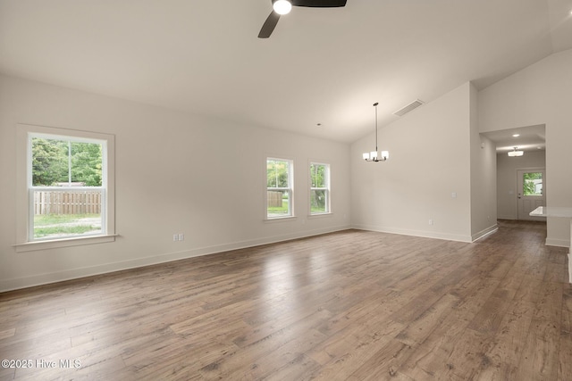 empty room featuring ceiling fan with notable chandelier, hardwood / wood-style floors, and vaulted ceiling