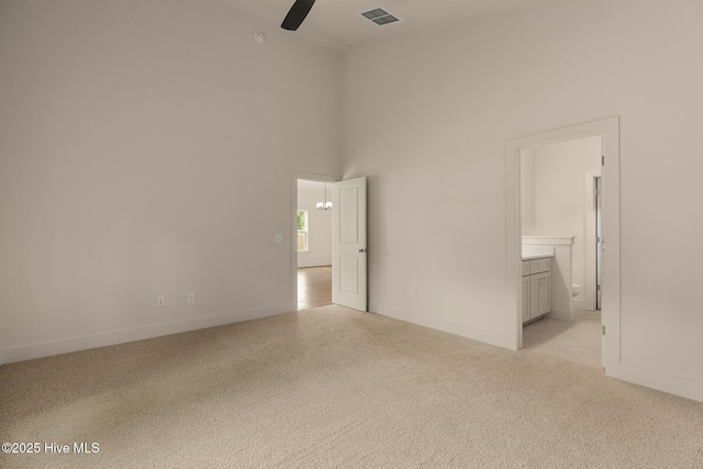 carpeted spare room featuring ceiling fan and a towering ceiling