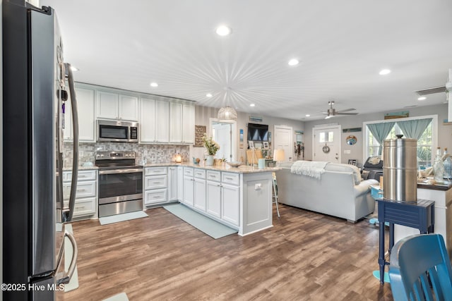 kitchen featuring dark wood-type flooring, appliances with stainless steel finishes, kitchen peninsula, and white cabinets