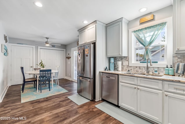 kitchen with light stone counters, sink, stainless steel appliances, and a healthy amount of sunlight