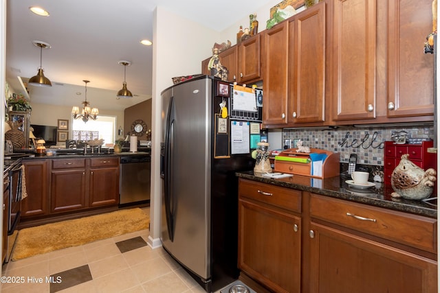 kitchen featuring a sink, appliances with stainless steel finishes, a notable chandelier, brown cabinets, and backsplash