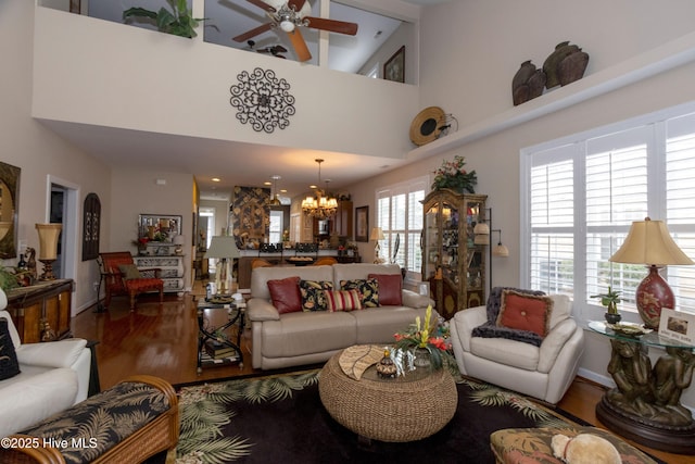 living room with wood finished floors, a high ceiling, and ceiling fan with notable chandelier