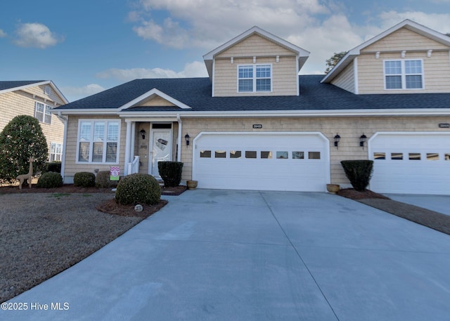 view of front facade with a garage, driveway, and a shingled roof