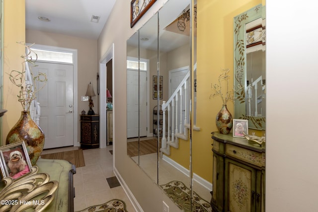 entrance foyer with visible vents, a healthy amount of sunlight, stairs, and baseboards