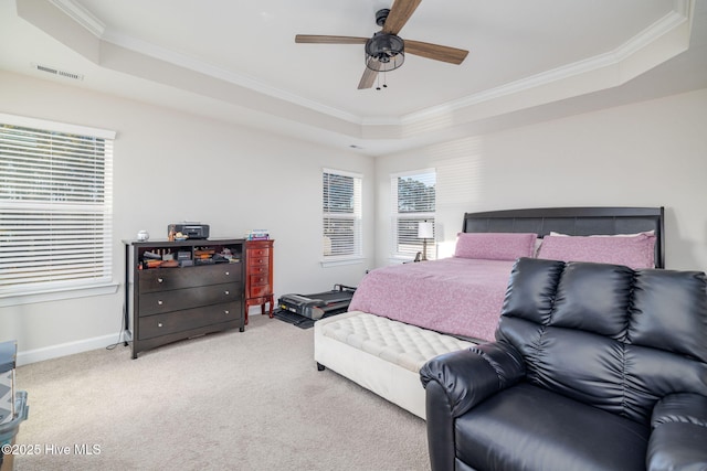 carpeted bedroom with a raised ceiling, crown molding, ceiling fan, and multiple windows