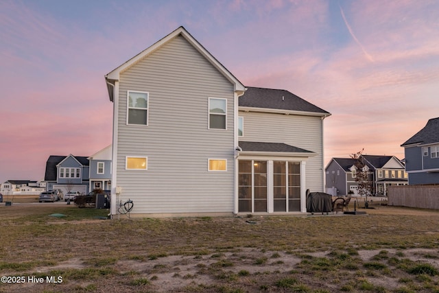 back house at dusk featuring a sunroom