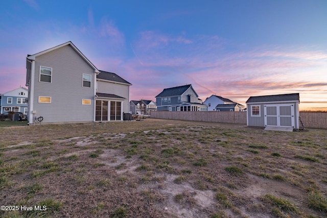 back house at dusk featuring a storage shed