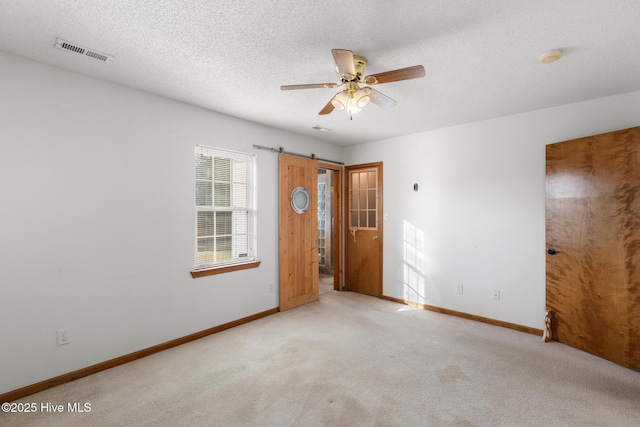 empty room with ceiling fan, a textured ceiling, and light carpet