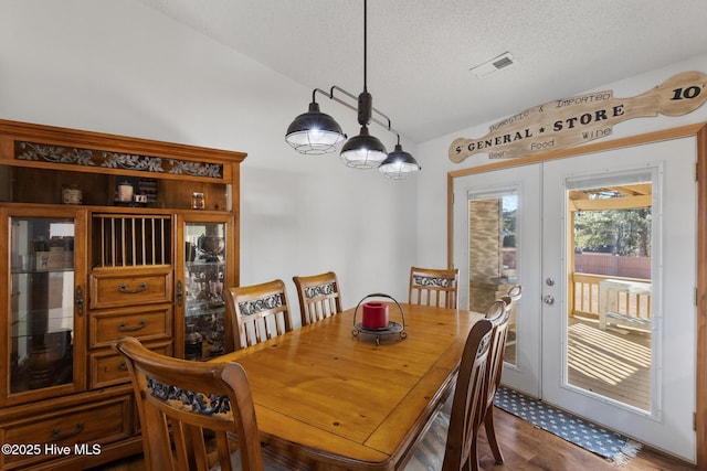 dining area featuring hardwood / wood-style floors, a notable chandelier, a textured ceiling, and french doors