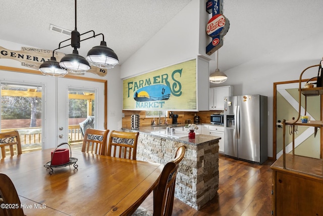 dining room with a textured ceiling, dark hardwood / wood-style flooring, french doors, and vaulted ceiling