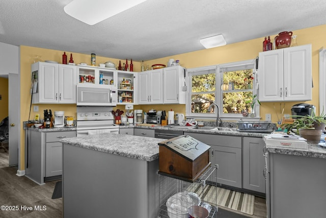 kitchen with a kitchen island, white appliances, gray cabinetry, and sink