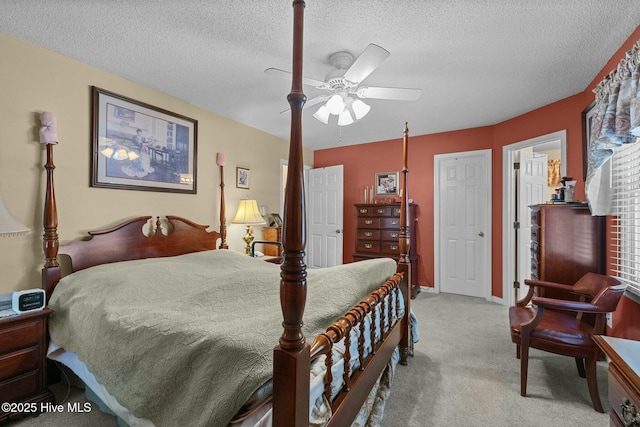 bedroom featuring a textured ceiling, light colored carpet, and ceiling fan