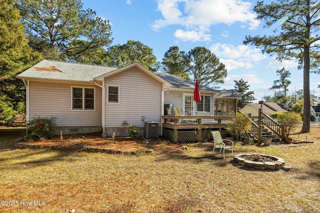 back of property with a sunroom, a wooden deck, an outdoor fire pit, a yard, and central air condition unit