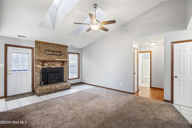 unfurnished living room featuring lofted ceiling with skylight, light colored carpet, a fireplace, and ceiling fan