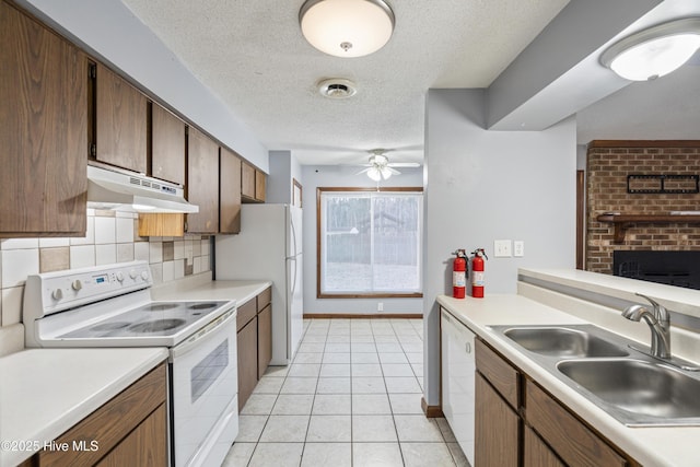 kitchen featuring sink, decorative backsplash, light tile patterned floors, white appliances, and a textured ceiling