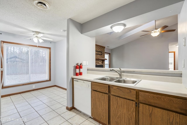 kitchen with vaulted ceiling, dishwasher, sink, light tile patterned floors, and a textured ceiling