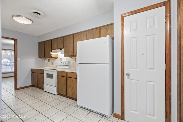 kitchen with light tile patterned floors, white appliances, and decorative backsplash