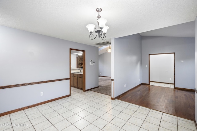 unfurnished room with light tile patterned floors, ceiling fan with notable chandelier, vaulted ceiling, and a textured ceiling