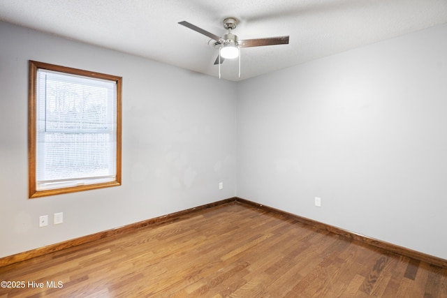 spare room with ceiling fan, light wood-type flooring, and a wealth of natural light