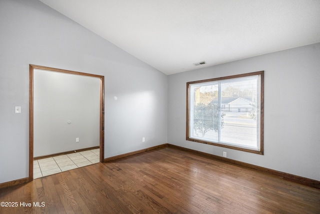 empty room featuring vaulted ceiling and light wood-type flooring