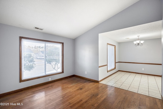 empty room with vaulted ceiling, light hardwood / wood-style floors, and a notable chandelier