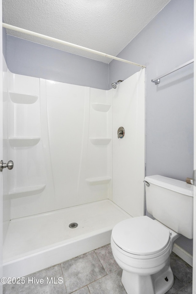 bathroom with walk in shower, toilet, tile patterned flooring, and a textured ceiling