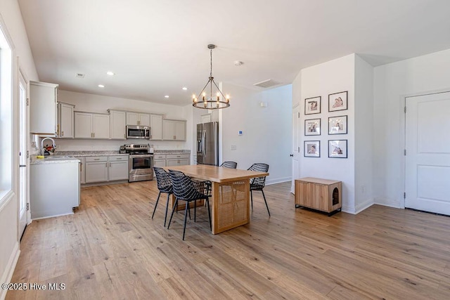 dining space featuring sink, a notable chandelier, and light hardwood / wood-style floors