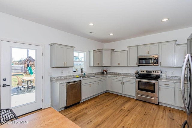 kitchen with sink, light hardwood / wood-style flooring, a healthy amount of sunlight, and appliances with stainless steel finishes