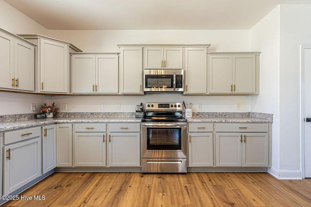 kitchen featuring stainless steel appliances, gray cabinetry, and light hardwood / wood-style floors