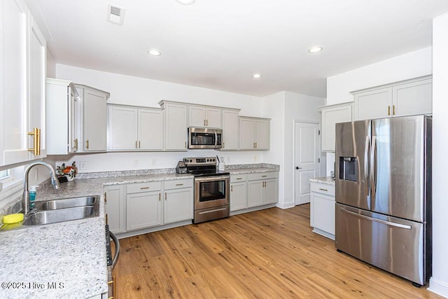 kitchen featuring sink, light hardwood / wood-style flooring, stainless steel appliances, and gray cabinets