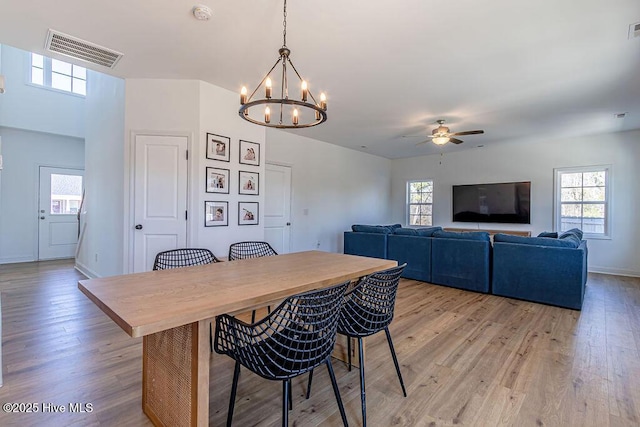 dining room featuring ceiling fan with notable chandelier, a wealth of natural light, and light wood-type flooring