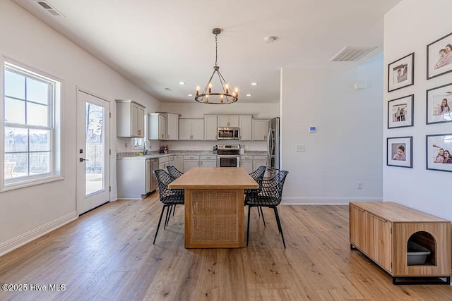 dining space featuring sink, light hardwood / wood-style flooring, and a notable chandelier