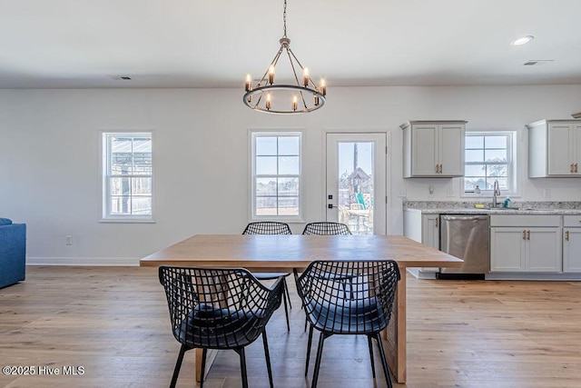 dining area with an inviting chandelier, sink, and light hardwood / wood-style floors