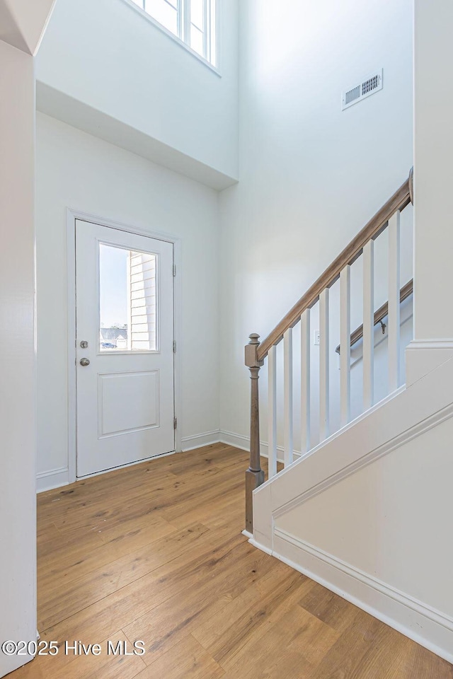 foyer entrance featuring a towering ceiling and light hardwood / wood-style floors