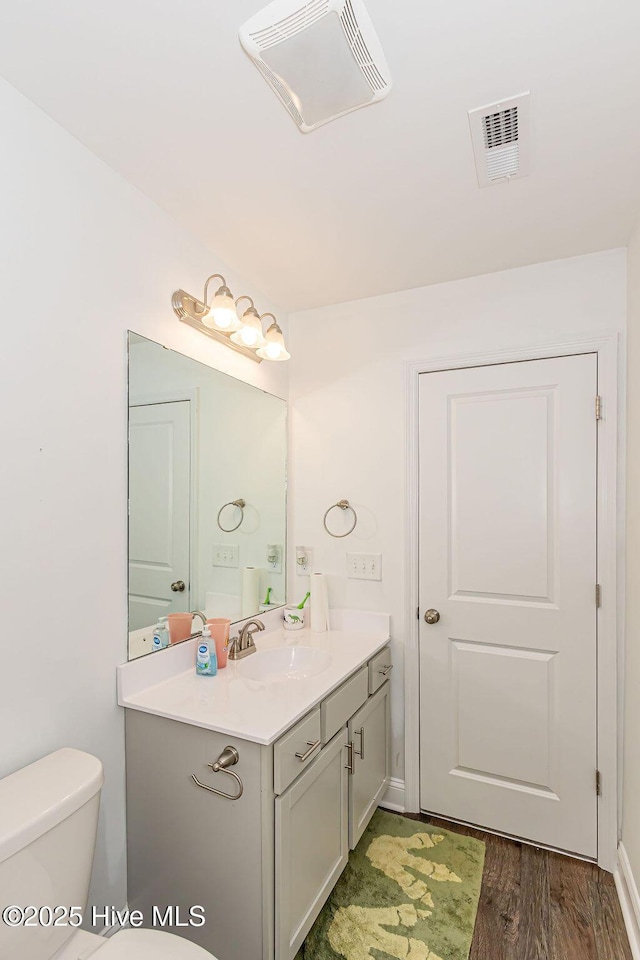 bathroom with hardwood / wood-style flooring, vanity, and toilet