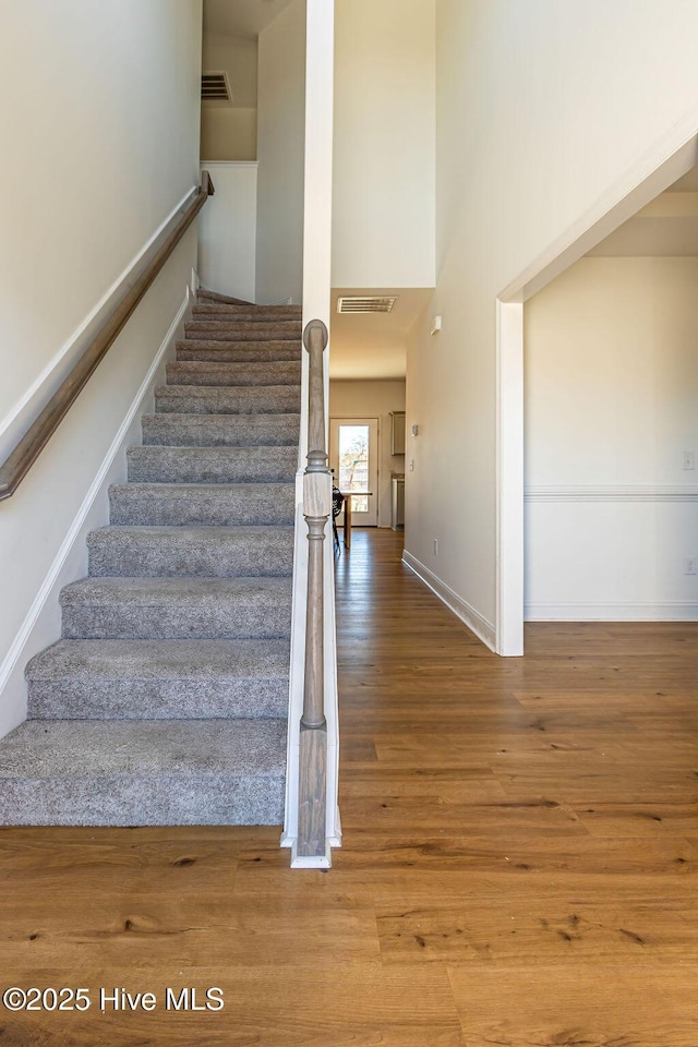 stairway featuring hardwood / wood-style floors and a towering ceiling