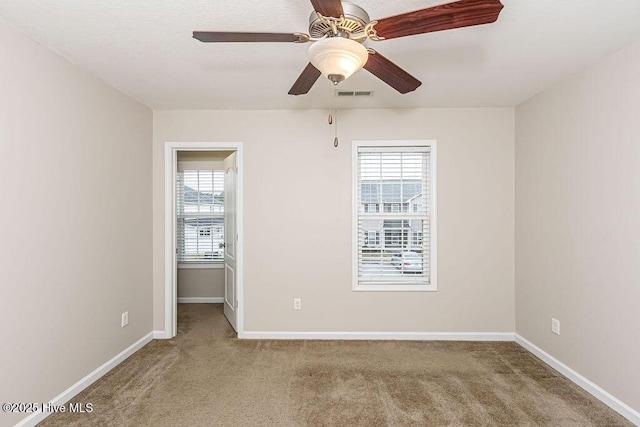 carpeted empty room featuring ceiling fan and a wealth of natural light