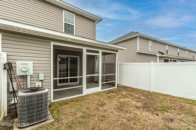 back of property with cooling unit, a lawn, and a sunroom